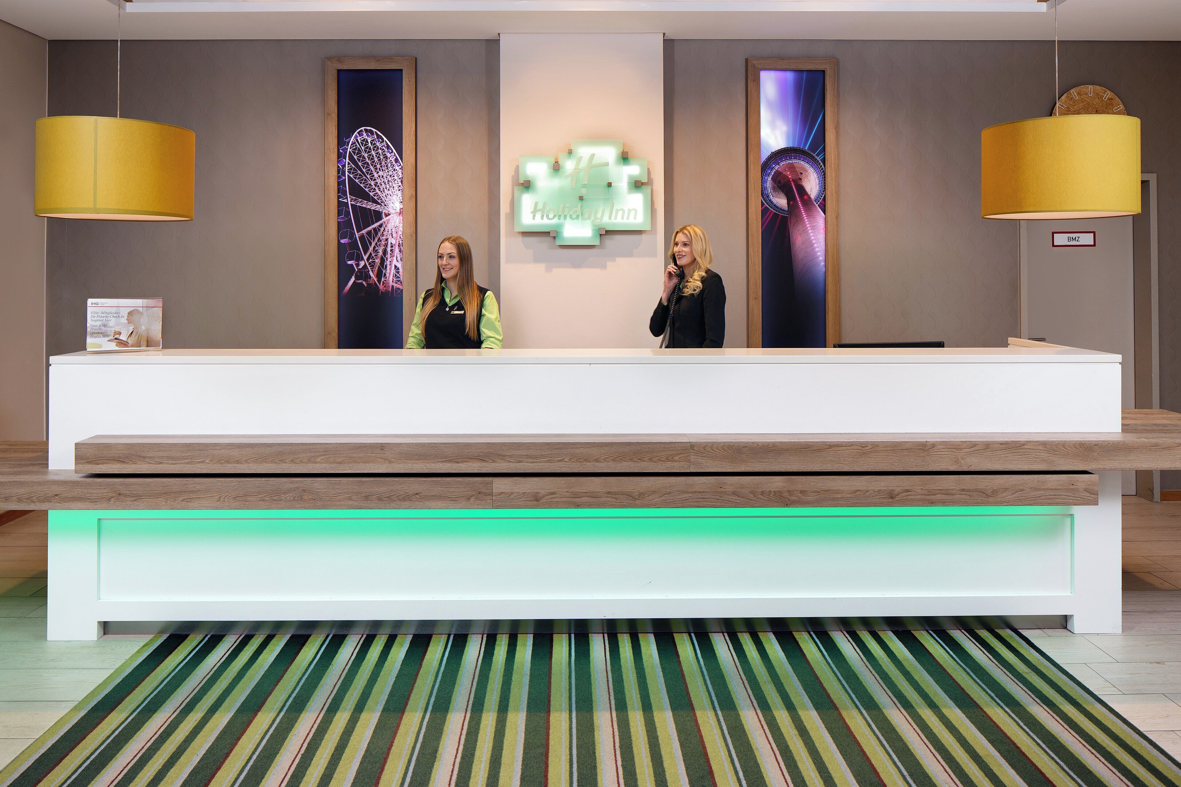 A hotel reception desk with a modern design, a digital display, and a nameplate.