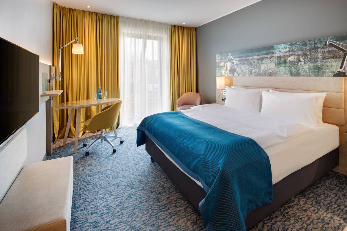 Habitación de hotel con una cama grande, un escritorio, una silla y un televisor.