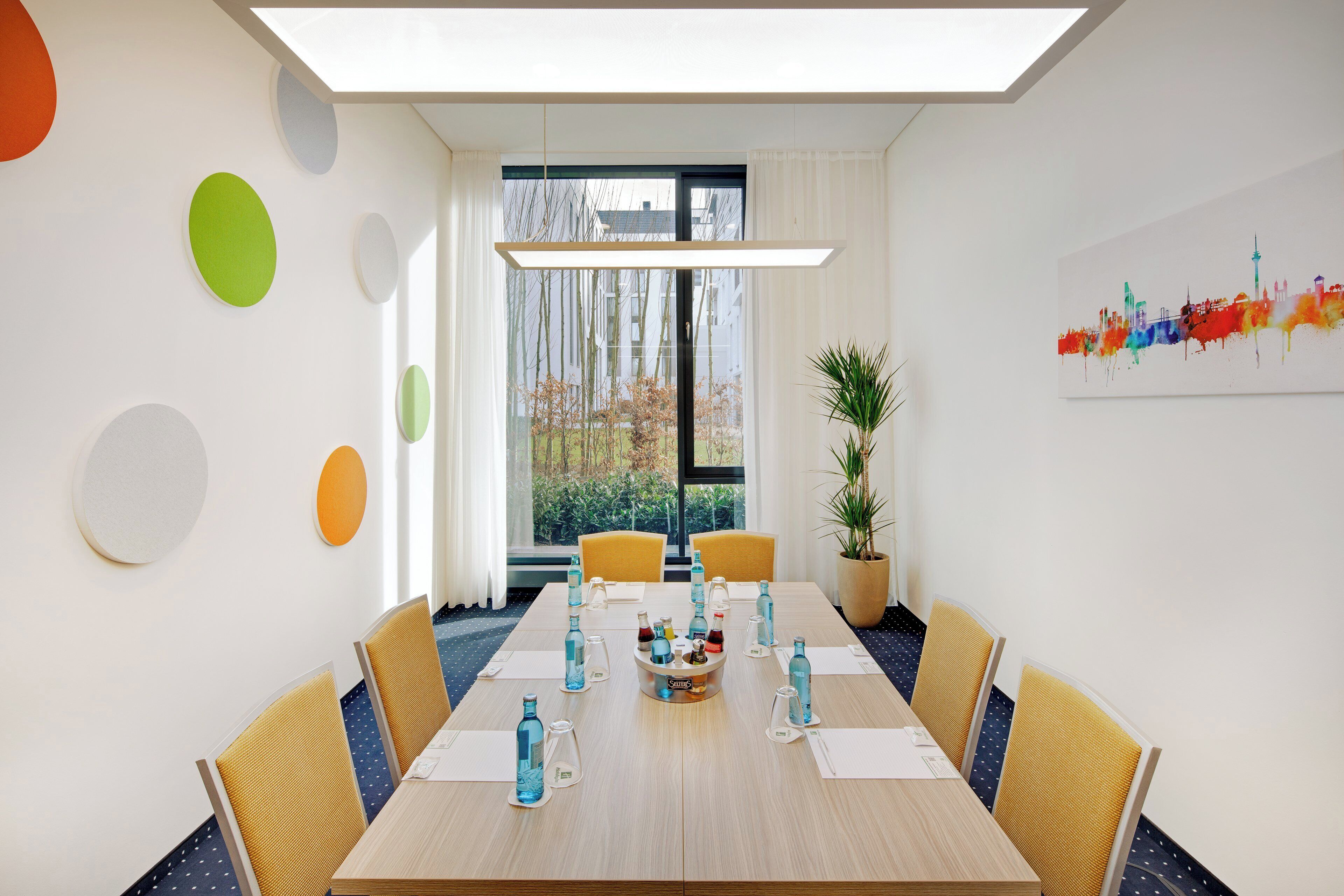 A conference room with a long table, chairs, and a potted plant.