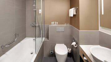 A modern bathroom with a bathtub, toilet, and sink, featuring a glass shower enclosure and a towel rack.