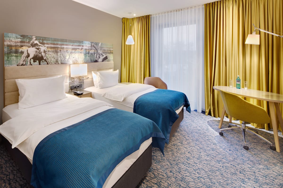 Habitación de hotel con dos camas, un escritorio y una silla.