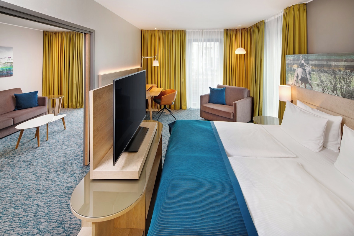 Una habitación de hotel con cama, televisión, escritorio y sofá.