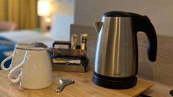 A wooden tray with a kettle, a coffee pot, and a mug on a table.