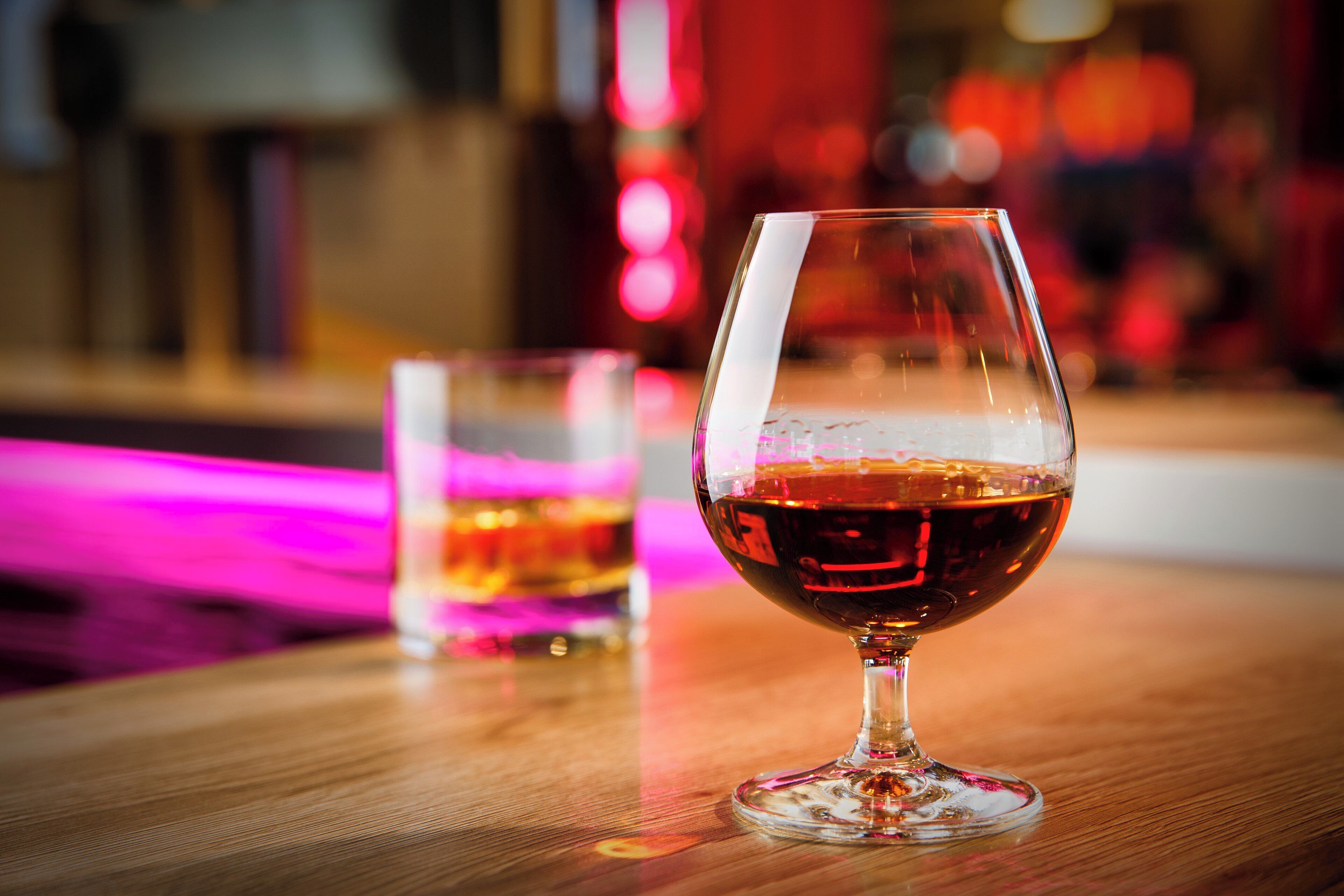 A glass of red wine on a wooden table with a blurred background.