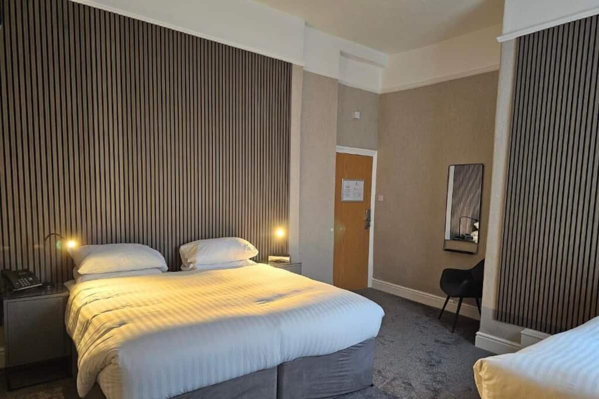 Ein Hotelzimmer mit einem großen Bett, Nachttischlampen, einem Schreibtisch und einem Sessel.