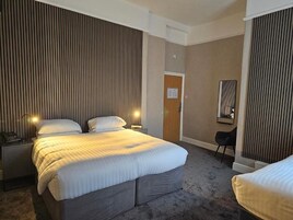 A hotel room with a large bed, bedside lamps, a desk, and a chair.