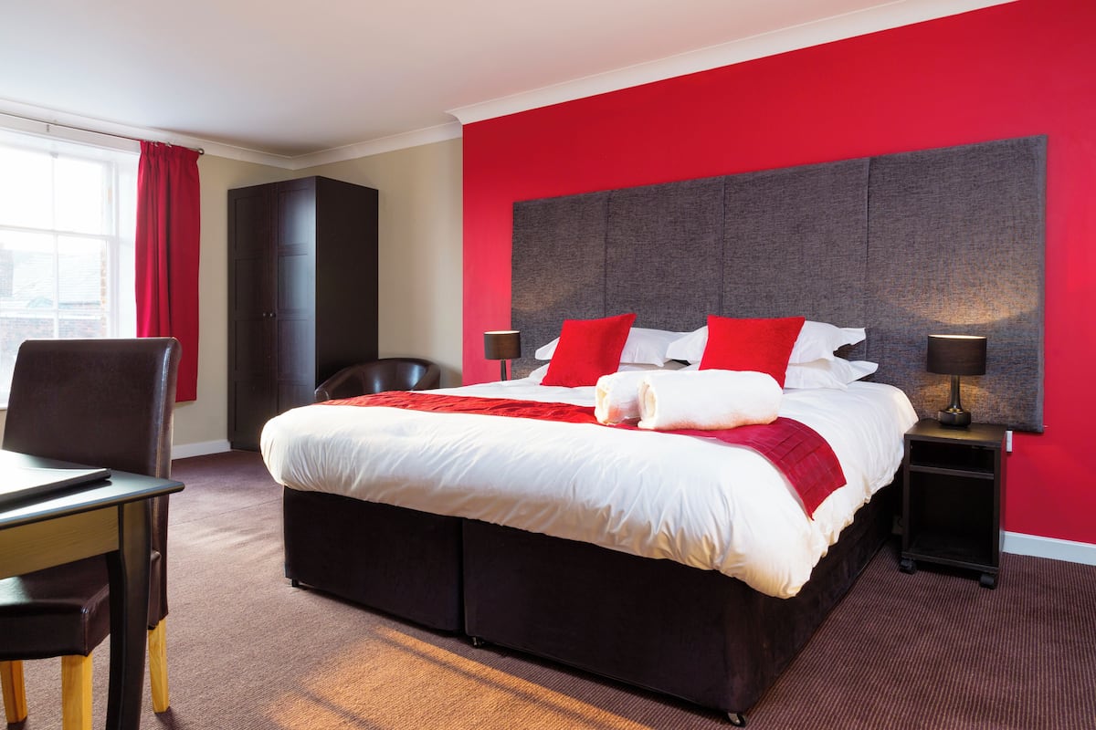 Ein Hotelzimmer mit einem großen Bett, einem Schreibtisch und einem Sessel.