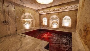 Un cuarto de spa con hidromasaje, piso de mármol y nichos decorativos en la pared.