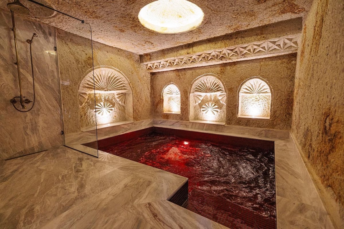 Un cuarto de spa con hidromasaje, piso de mármol y nichos decorativos en la pared.