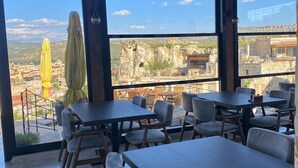 Un restaurante con terraza, amplios ventanales y vistas del paisaje circundante.