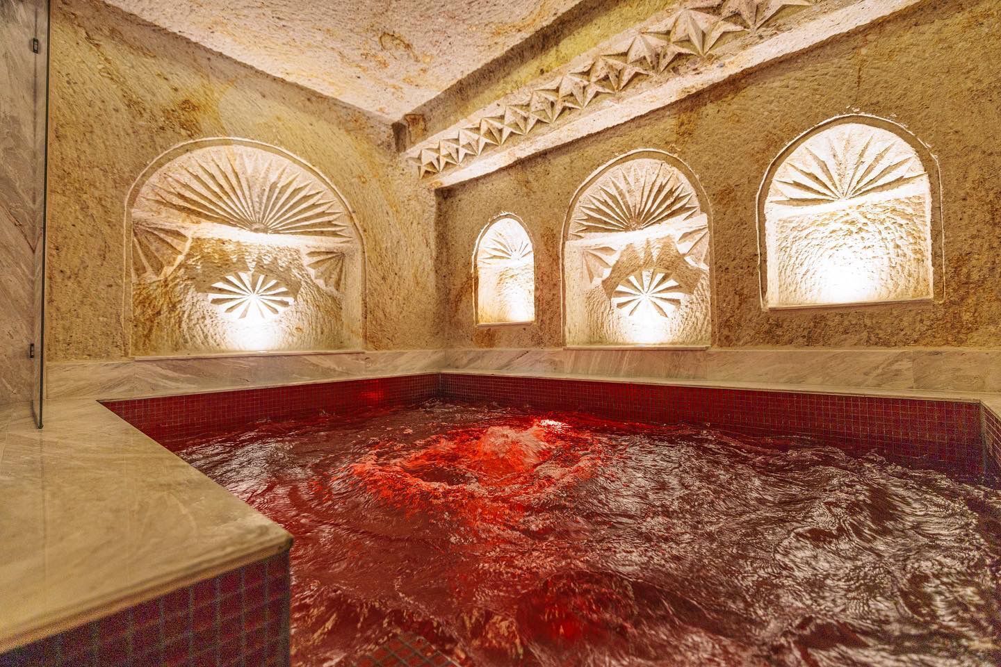 Un baño termal con tres ventanales de arco, cada uno con un diseño de sol.