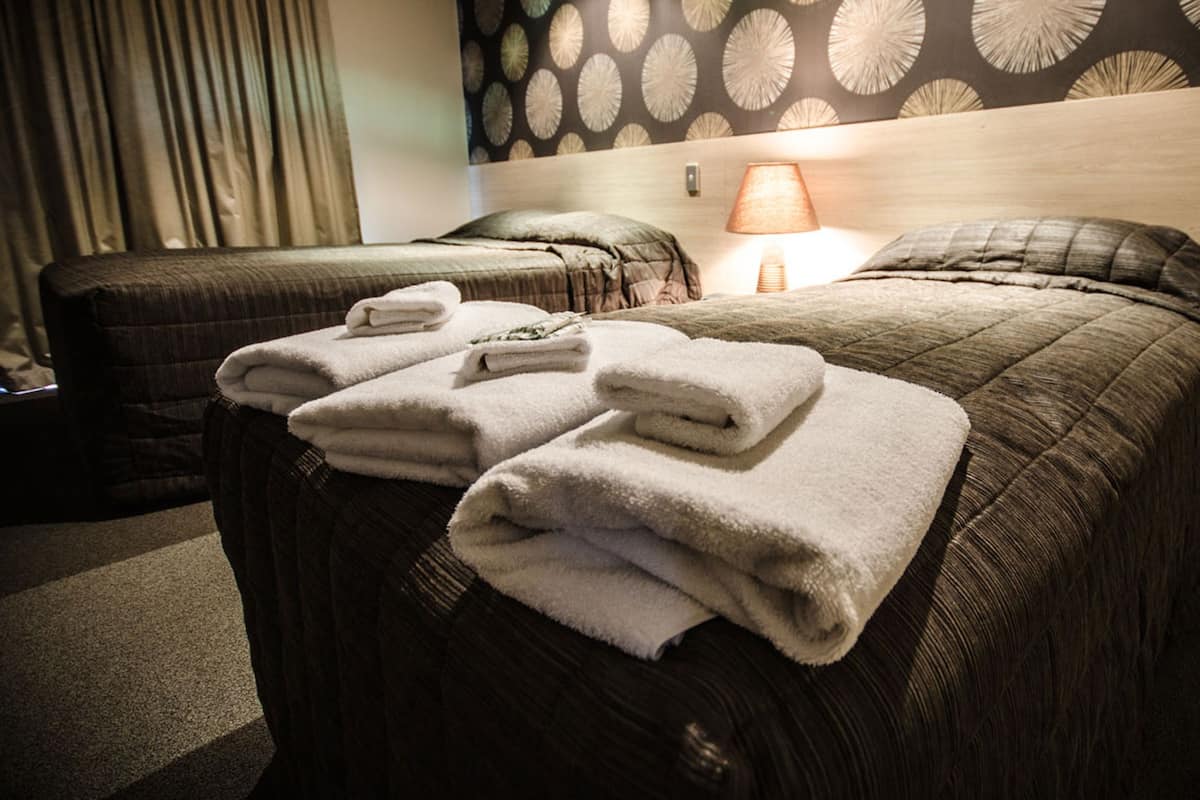 A hotel room with a bed, a chair, and a lamp.