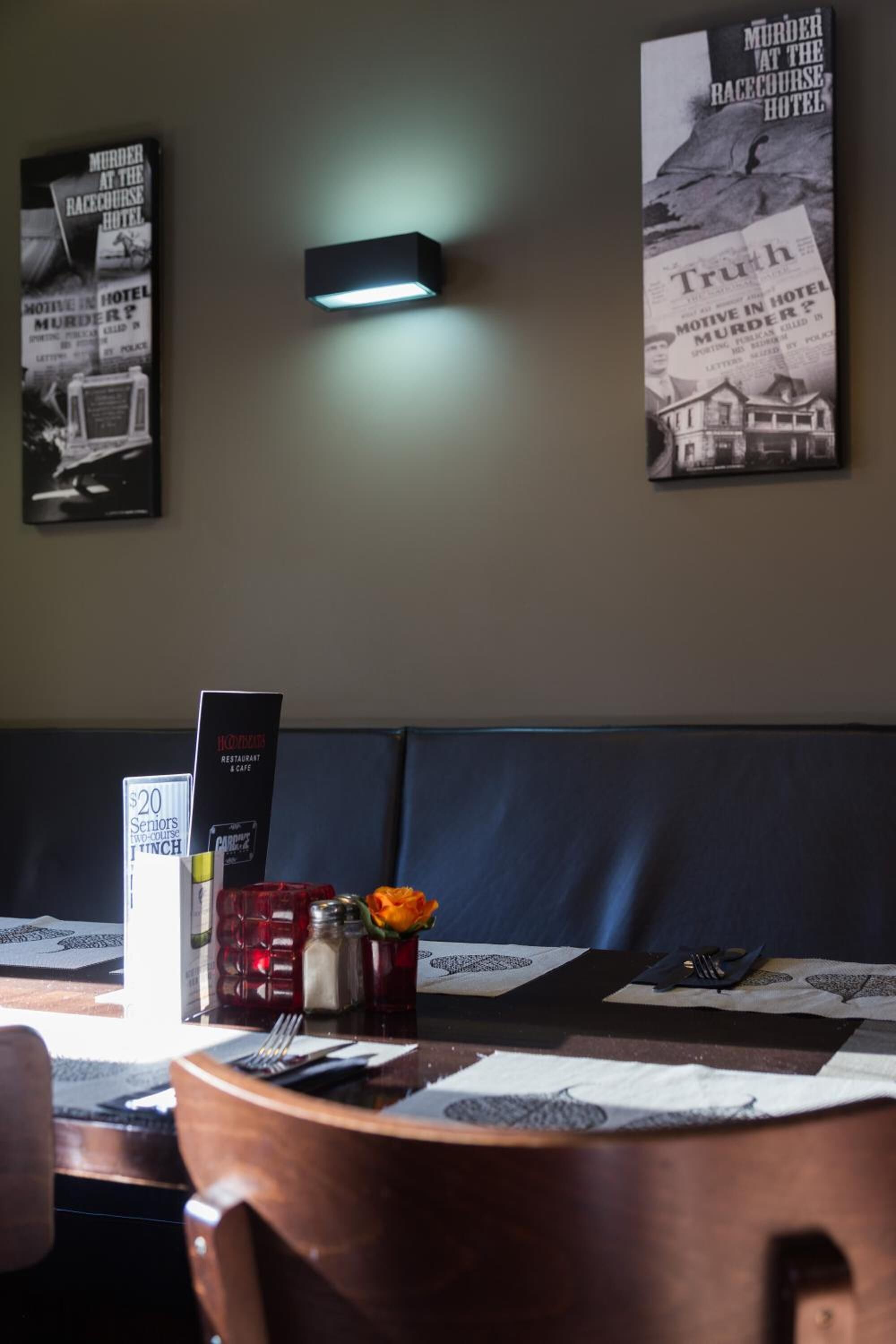 Un restaurante con zona de asientos tipo cabina, un atril para el menú y decoración de pared con carteles de estilo antiguo.