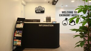 A reception desk with a sign reading "Economy Hotel" and a welcome sign. There is a plant to the right and a bulletin board with various notices. - Ekonomy Hotel Mokpo (Mokpo)