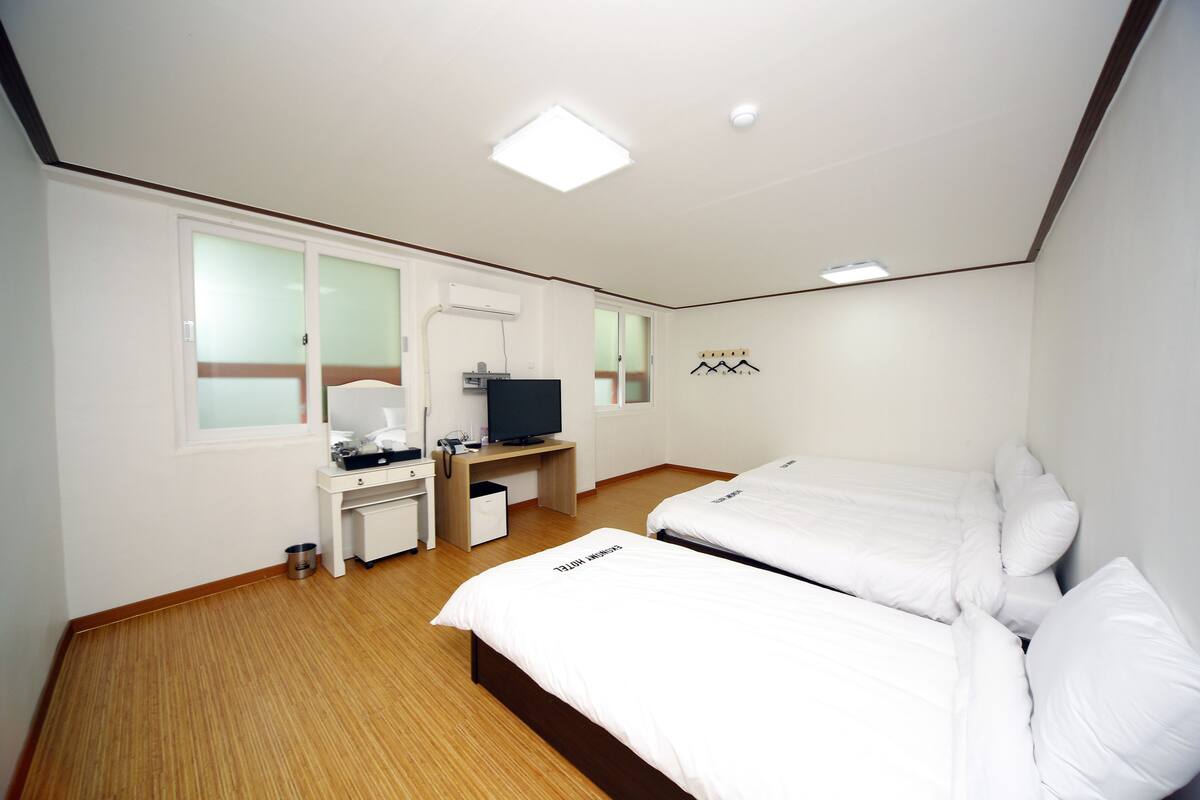 Habitación de hotel con dos camas, un escritorio, un televisor y una ventana.