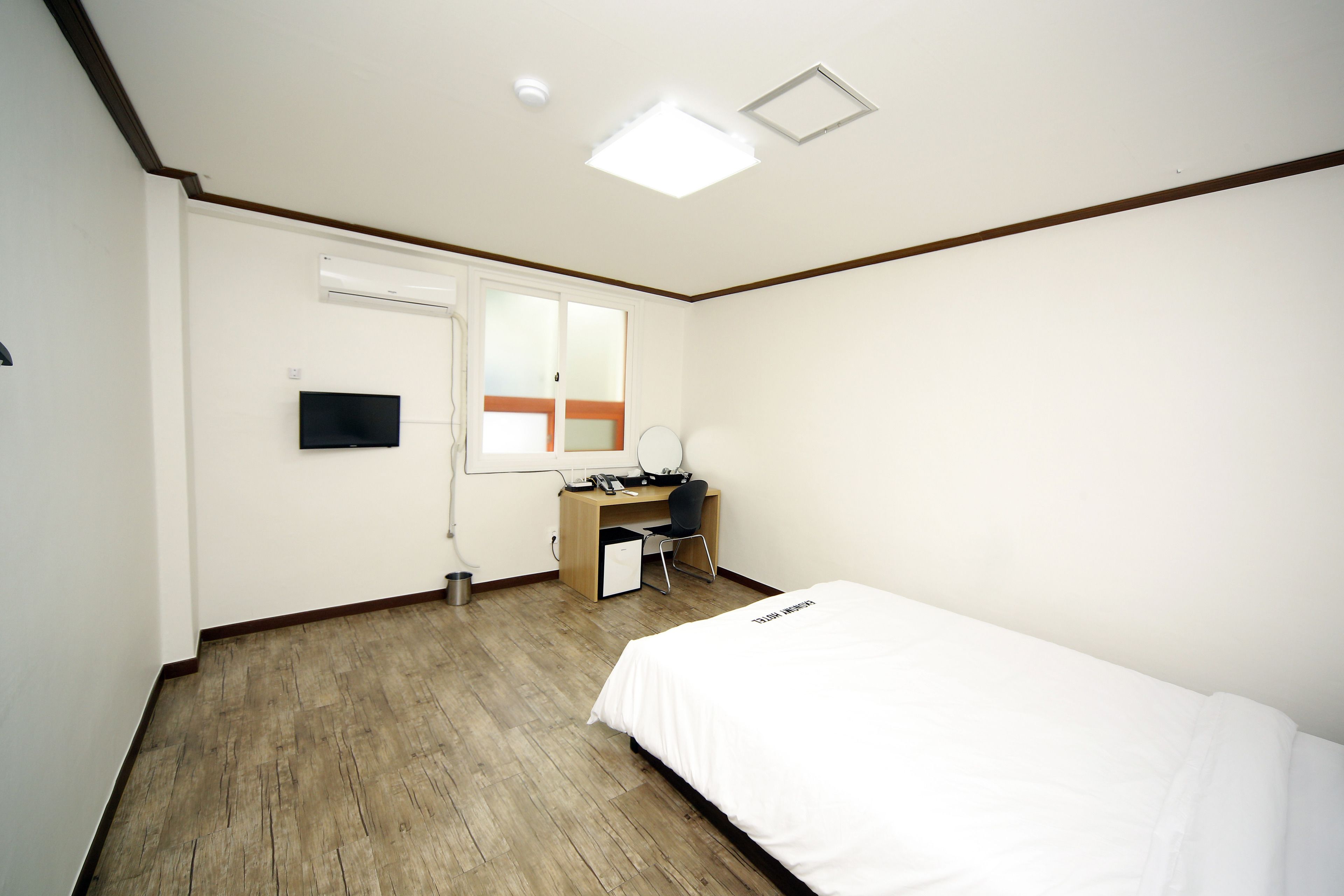 Un dormitorio con cama, escritorio, silla, televisor y ventana.