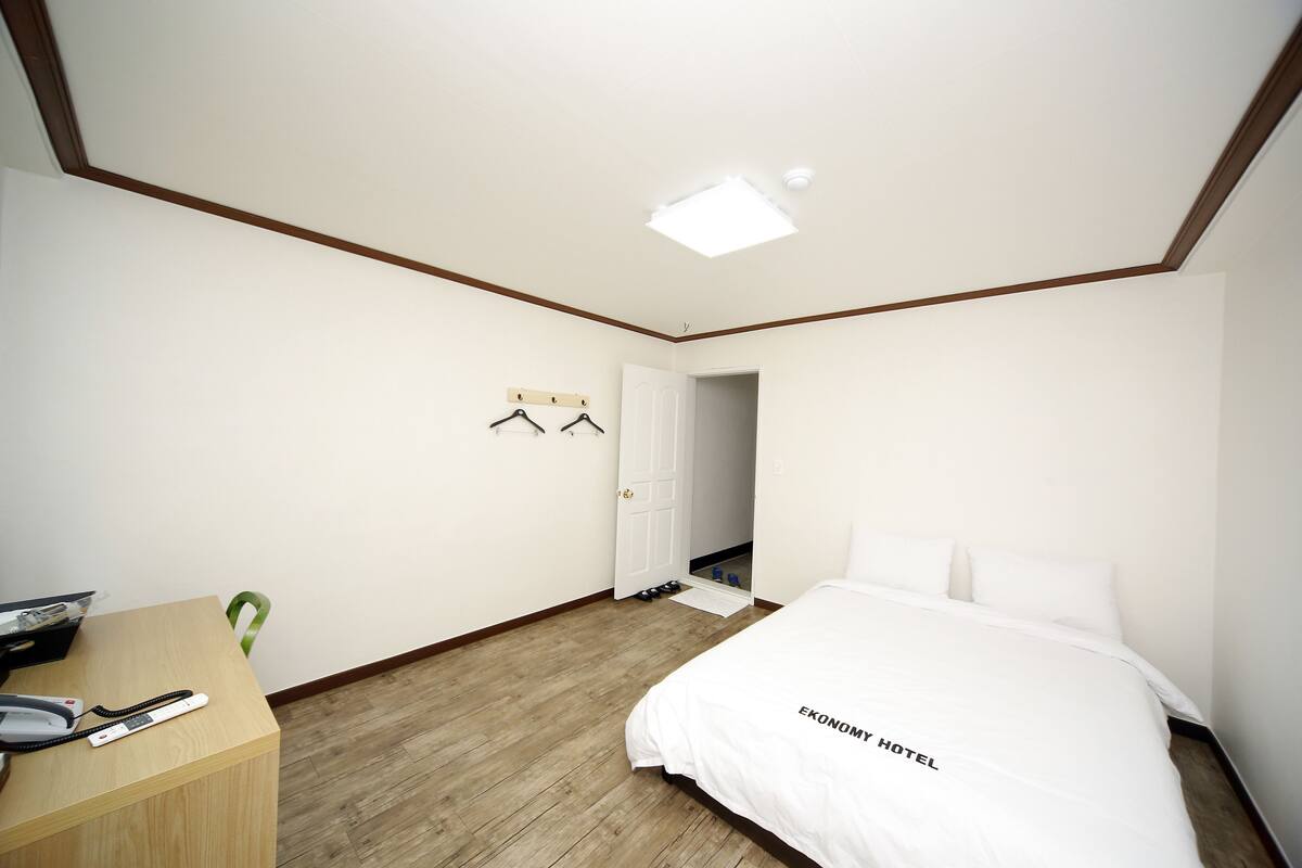 Una habitación de hotel con una cama, un escritorio con teléfono y un perchero.