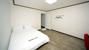 A hotel room with a bed, a red chair, a coat rack, and a door leading to another room. - Ekonomy Hotel Mokpo (Mokpo)