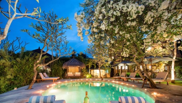 Zona de piscina con sillas de descanso y una mesa con velas.