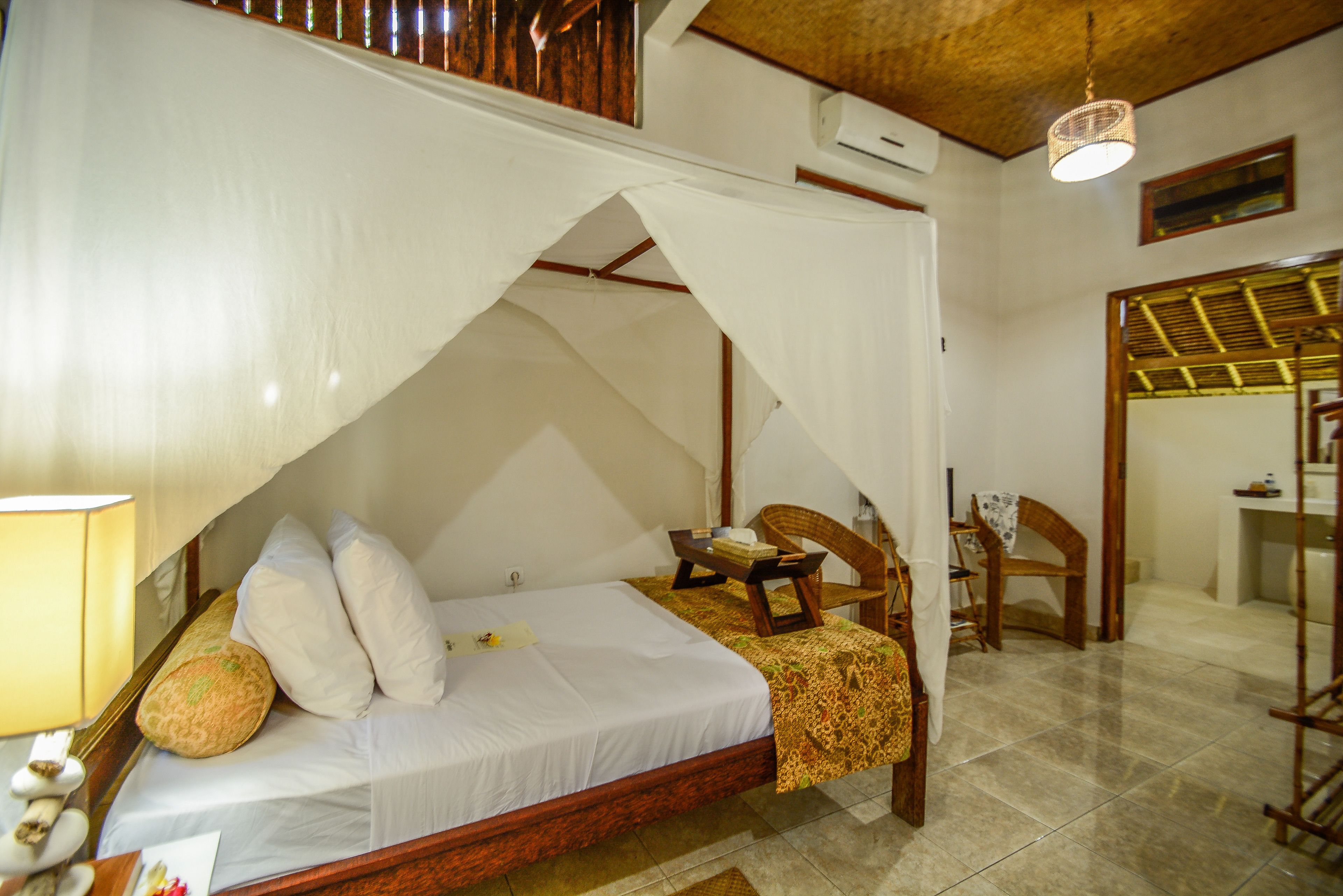 Una habitación con cama, una silla, una mesa y una lámpara colgante.