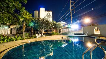A swimming pool with lounge chairs and a building in the background.