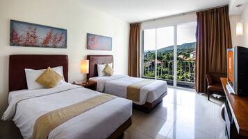 A hotel room with two beds, a TV, a balcony with a view of the mountains, and artwork on the walls.