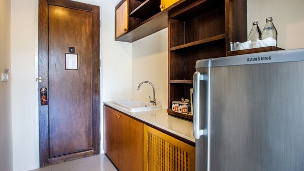 Una cocina con un refrigerador de acero inoxidable, un lavamanos, armarios de madera y una puerta con un letrero.