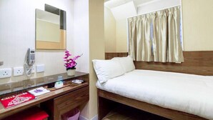 A hotel room with a single bed, a bedside table with a phone, a vase with flowers, and a red booklet on the desk. - Shanghai Red (Kowloon)