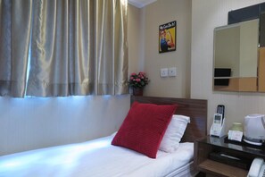 A hotel room with a bed, a red pillow, a bedside table with a phone, a coffee maker, and a mirror. - Shanghai Red (Kowloon)