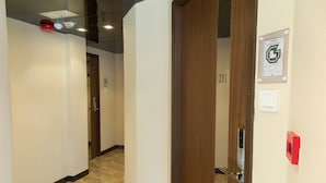 A hallway with a wooden door labeled "201" and a fire alarm on the wall. - Shanghai Red (Kowloon)