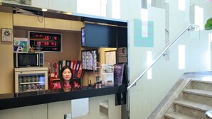 A reception area with a digital clock, vending machines, and a staircase. - Shanghai Red (Kowloon)