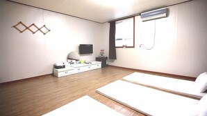 A hotel room with a wooden floor, a white dresser with drawers, a flat-screen TV mounted on the wall, a window with curtains, and a bed with white bedding. - Songnisan Grand Hotel & Condo (Boeun)