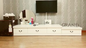 A white TV stand with a flat-screen TV, a mirror, and various items on top. - Songnisan Grand Hotel & Condo (Boeun)