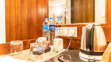 Mostrador de recepción de hotel con una tetera, botellas de agua, vasos y una caja de pañuelos.