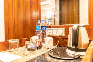 Mostrador de recepción de hotel con una tetera, botellas de agua, vasos y una caja de pañuelos.