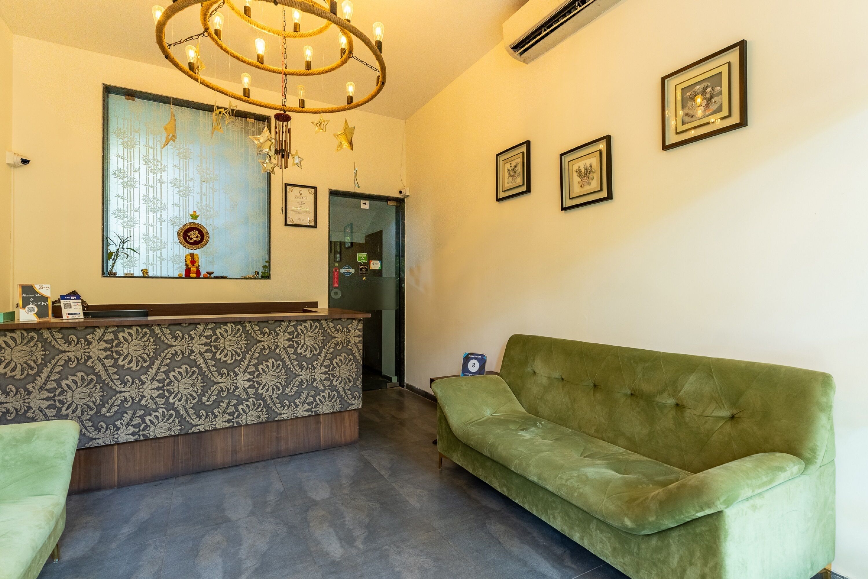 Un espace d’accueil avec un mur décoré de motifs, un canapé vert et un lustre.