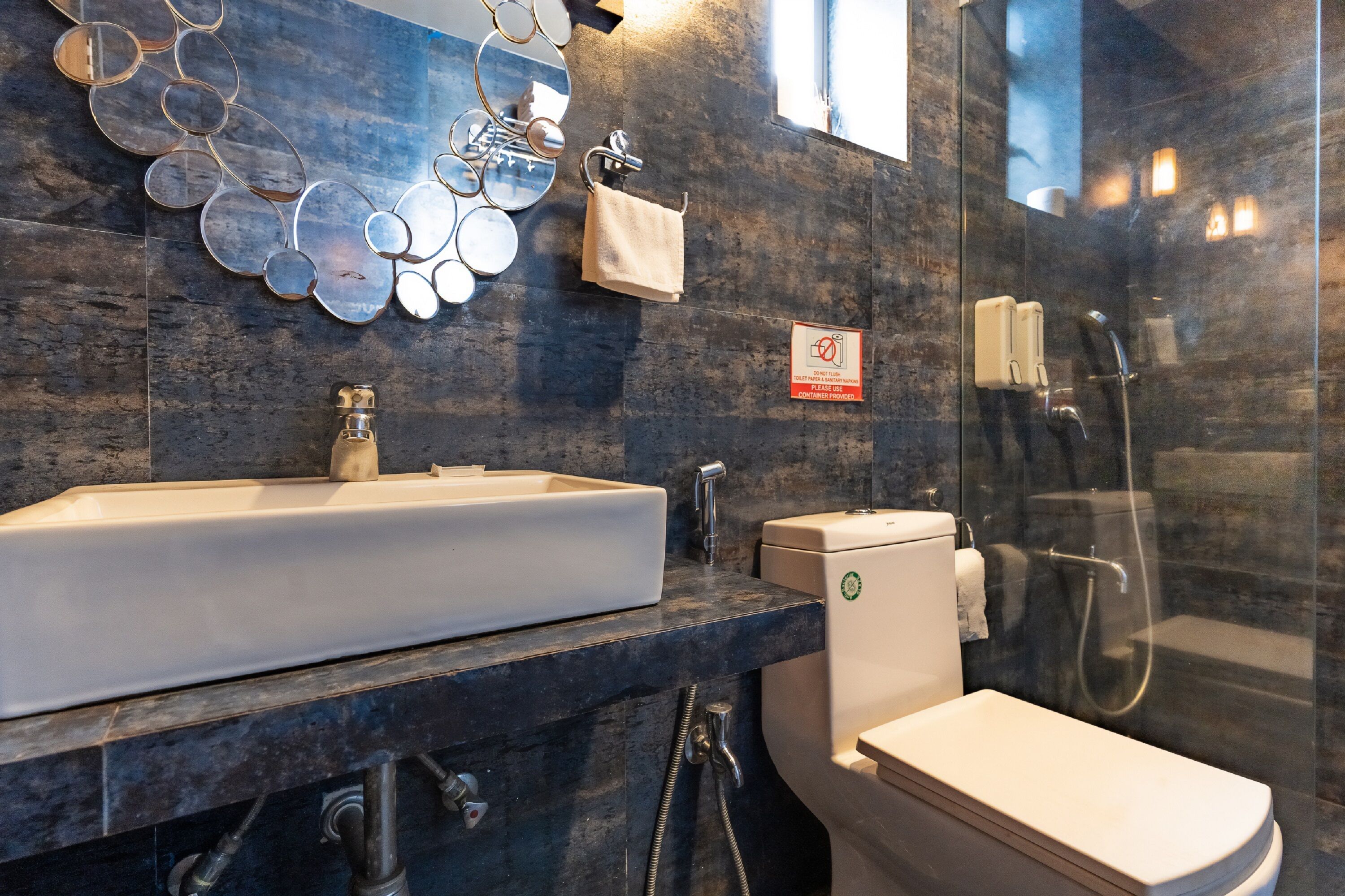 A modern bathroom with a large sink, toilet, and glass-enclosed shower.