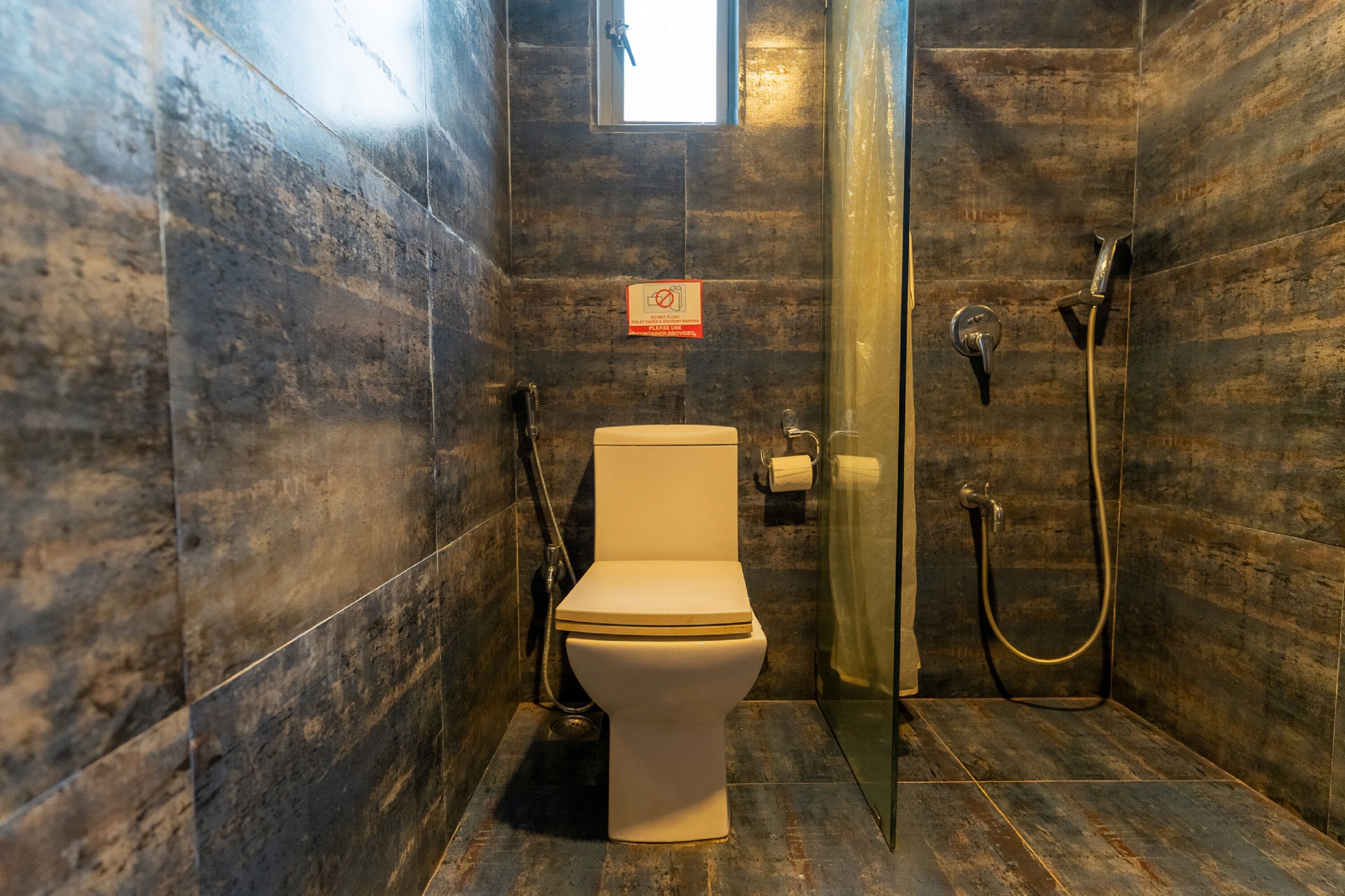 Une salle de bain avec des toilettes, une douche et une porte en verre.