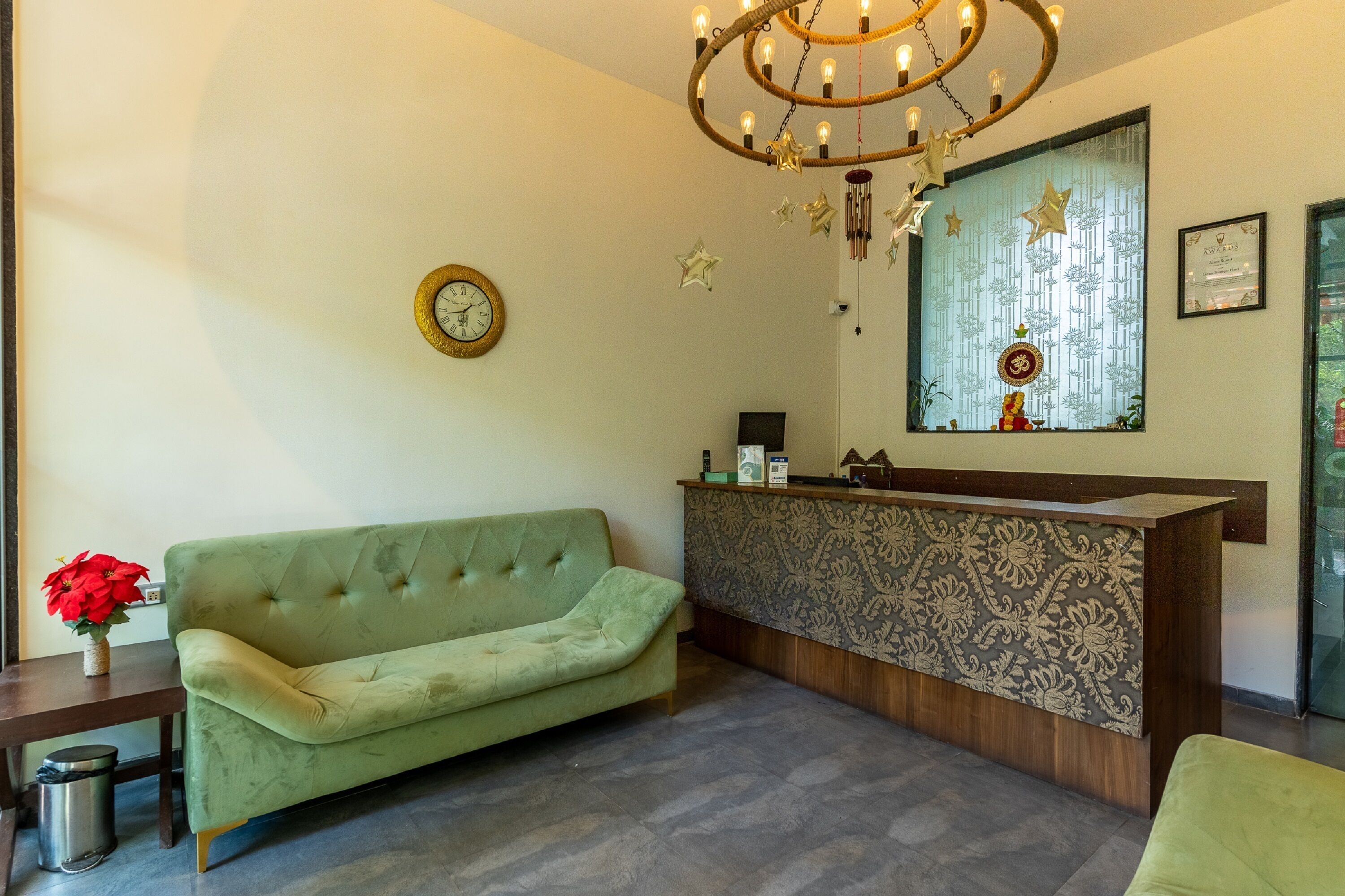 A reception area with a green sofa, a wooden reception desk, a clock, and a chandelier.