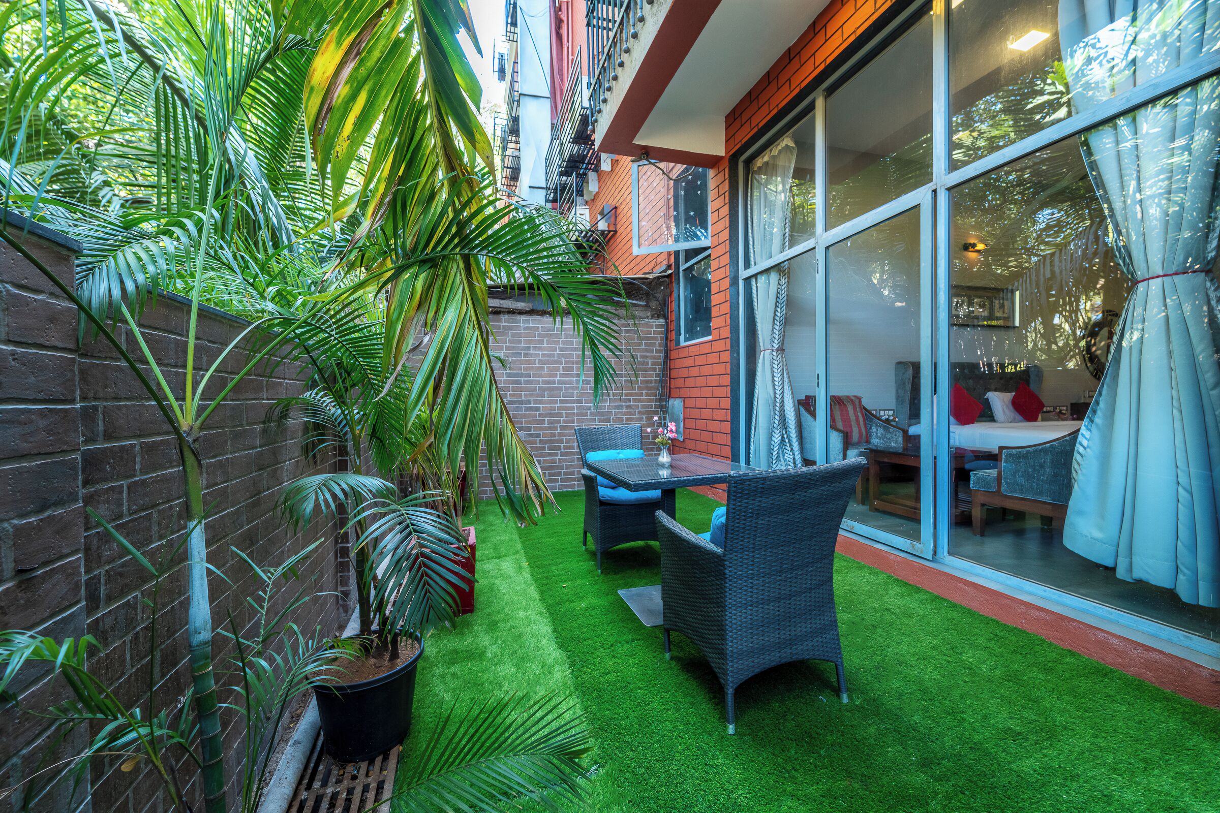 A patio with artificial grass, wicker furniture, and potted plants.