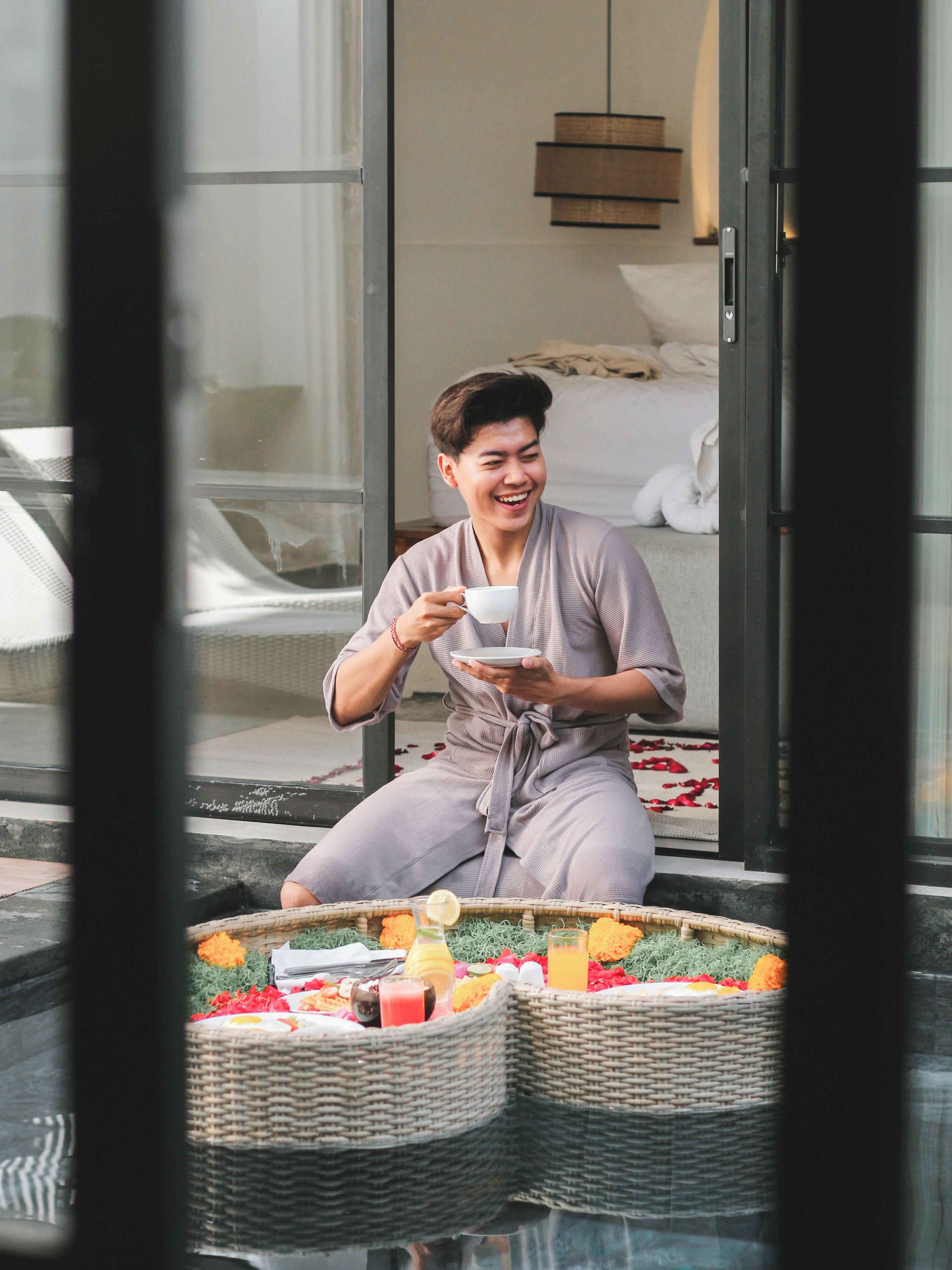 A person sitting on a balcony with a wicker basket containing fruits and flowers.