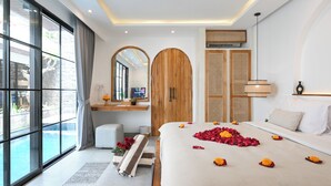 Quarto de hotel moderno com uma cama grande, vista para uma piscina, guarda-roupa de madeira e um espelho.