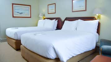 A hotel room with two beds, a desk, and a chair.