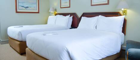 A hotel room with two beds, a desk, and a chair.
