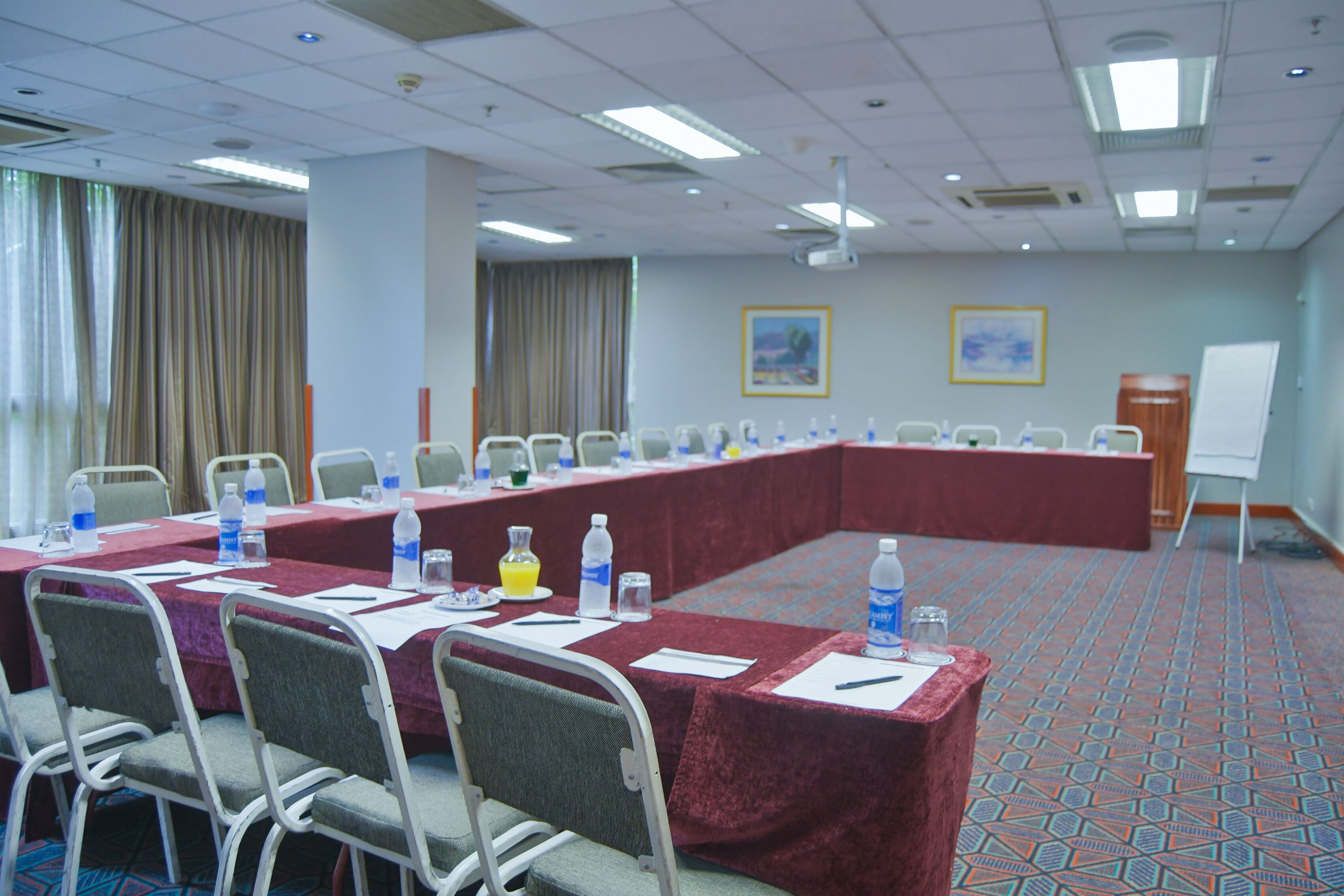 Un salón de conferencias con una larga mesa, sillas, botellas de agua y una pizarra.