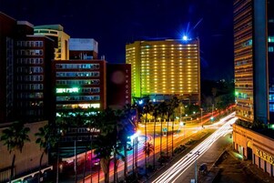 Un paisaje urbano nocturno con edificios iluminados, incluyendo un hotel destacado con un letrero encendido.