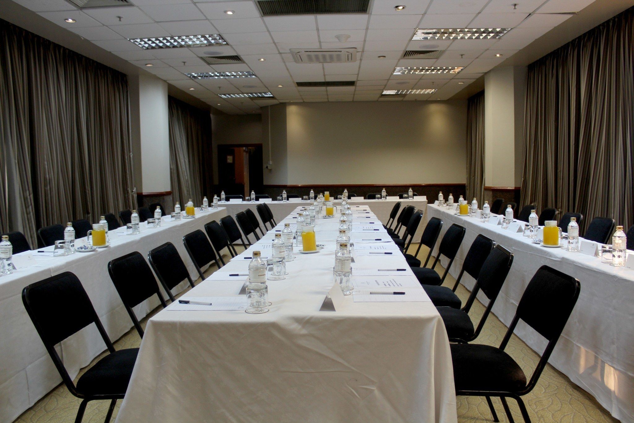 A conference room with a long table set for a meeting, equipped with water bottles, glasses, and nameplates.