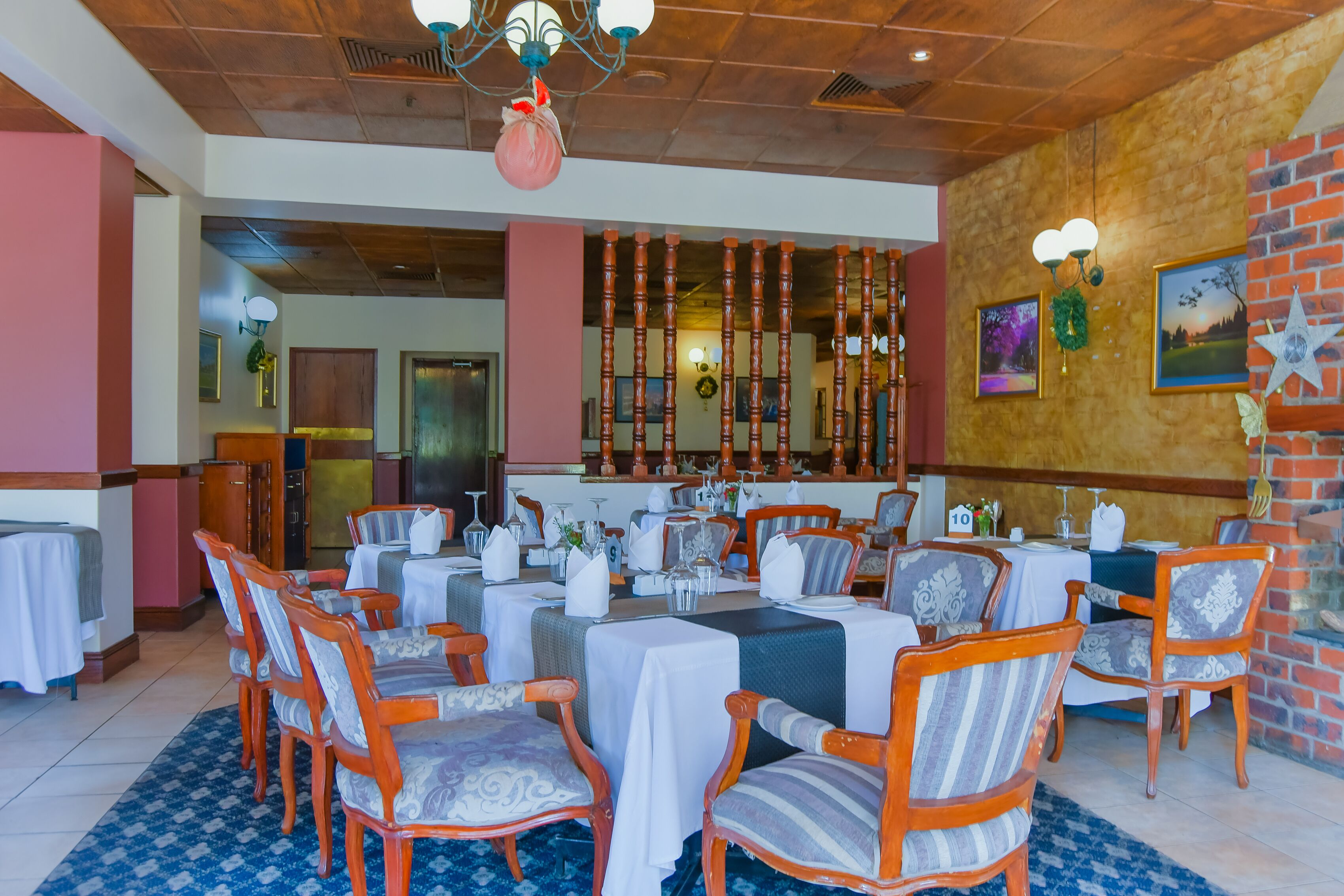 A restaurant with wooden chairs and tables, a brick wall, and a chandelier.