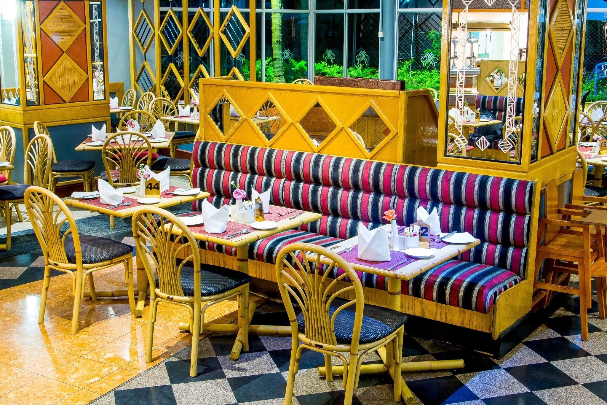 A restaurant with striped seating, wooden chairs, and a checkered floor.