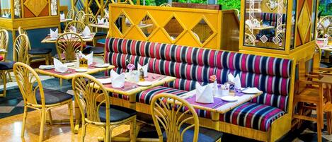 A restaurant with striped seating, wooden chairs, and a checkered floor.